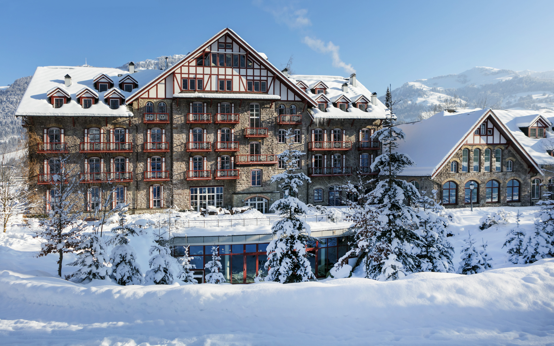 Snowy exterior of Grand Hotel with mountains in the background