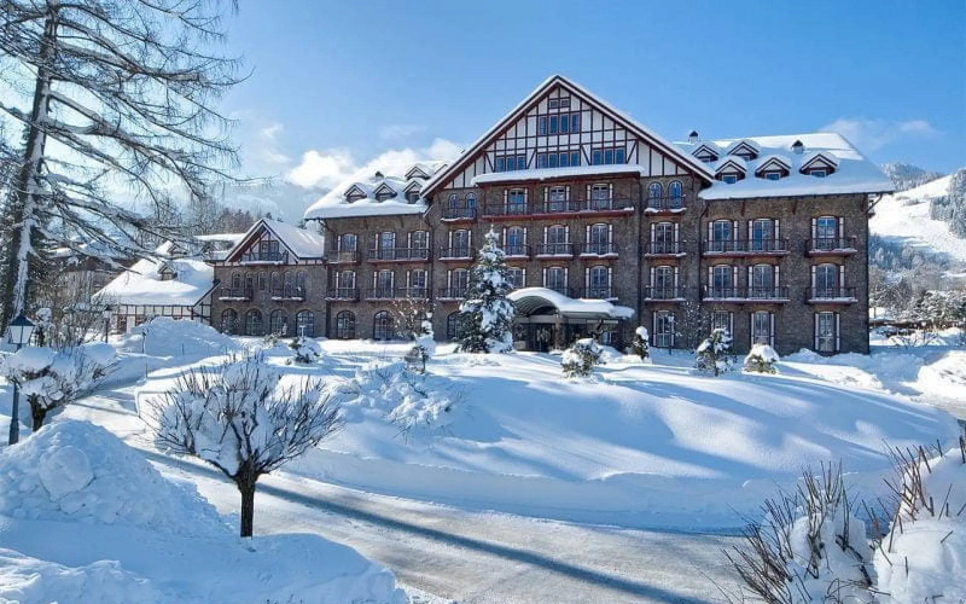 Snow-covered grand hotel with a large facade and surrounding trees