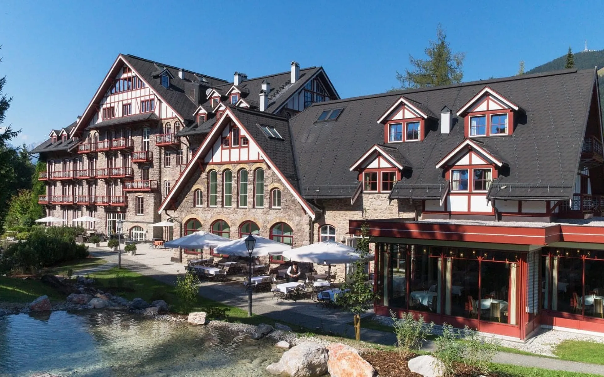 Scenic view of Grand Hotel Kitzbühel surrounded by greenery and a pond